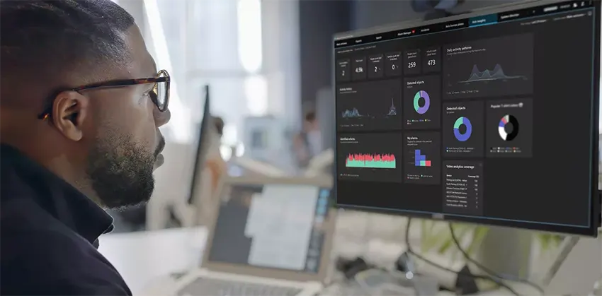 a man looking to monitor which is showing axis potimizer in milestone xprotect software